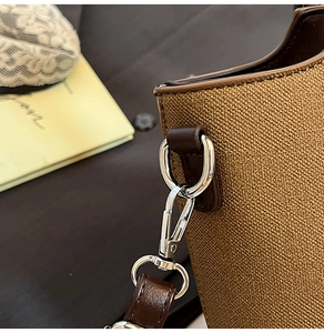 Detail of silver metal hooks and brown leather strap on textured crossbody bag