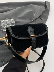 Minimalist black matte underarm bag with gold hardware on a grey blazer background