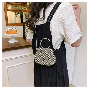 Detail of handmade pearl beaded handbag with round metal handle and silver chain strap