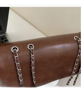 Nahaufnahme der braunen Ledertasche mit silberner Metallkette und glänzender Oberfläche