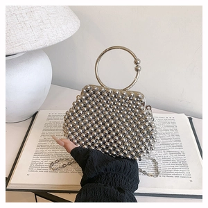 Detail of silver beaded evening bag with metal ring handle on open book pages