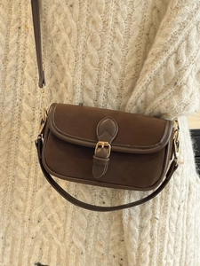Brown matte underarm bag with gold vintage buckle on white knit sweater background