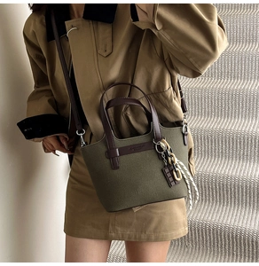 Olive green canvas crossbody bag styled with khaki trench coat on model on stairs