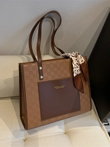 Sac cabas en cuir marron à damier avec foulard léopard sur un canapé crème