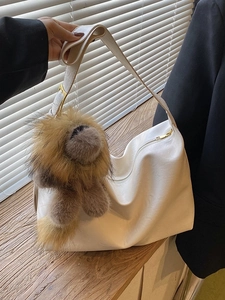 Minimalist white PU leather tote bag with a brown lion charm and a wide shoulder strap