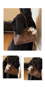 Detail view of large retro dark brown tote bag with plush puppy pendant and buckle accent