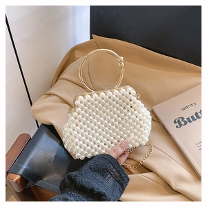 Detail of elegant handmade pearl beaded handbag with golden metal round handle and chain