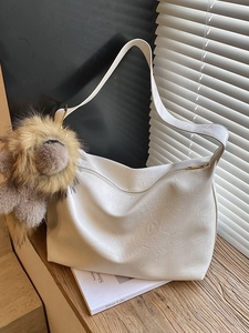 White large capacity faux leather tote bag with lion pendant in natural sunlight