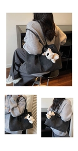 Detail of black suede tote bag with cute white plush dog charm and long shoulder straps