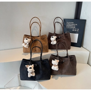 Detailed view of four suede tote bags in earthy tones with decorative plush charms