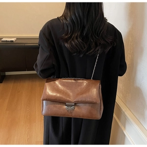 Nahaufnahme der dunkelbraunen Vintage-Ledertasche mit Silberkette und Metallschnalle
