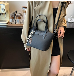 Close-up of black leather handbag featuring a stylish silk scarf and chocolate charm