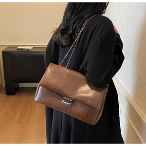 Detailansicht einer braunen Ledertasche mit silberner Kette und Schnalle in der Rückansicht