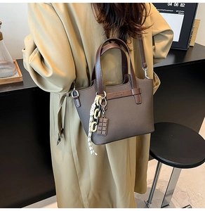 Detail of dark brown PU leather tote bag with braided charm and adjustable shoulder strap