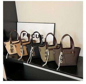 Detail of five earth-toned tote bags with chocolate pendants on a modern display shelf