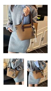 Detail of canvas tote bag with brown leather handles and a chocolate charm pendant