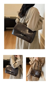 Detail der dunkelbraunen Ledertasche mit Silberschnalle und metallischer Kette