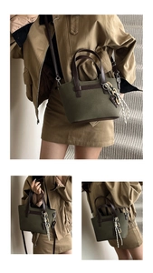 Detail of olive canvas tote bag with dark brown leather handles and decorative pendant