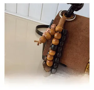 Detail of handmade wooden bead charm with hemp rope on brown suede handbag strap