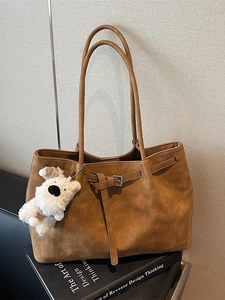 Brown suede tote bag with plush dog charm and buckle strap for daily commuting