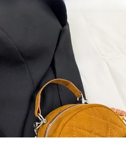 Gros plan sur un sac à main en daim matelassé beige avec fermeture éclair argentée