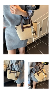 Detail of beige woven tote bag featuring dark brown leather trim and a chocolate charm