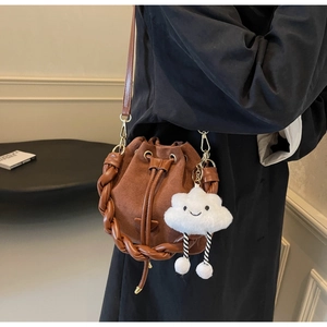 Détail du sac seau en daim marron avec bordure tressée et pendentif nuage mignon