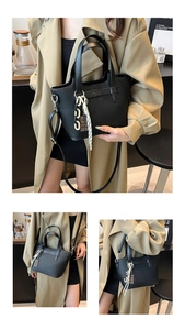 Detail of black pebbled leather tote bag with fashion charm and adjustable shoulder strap