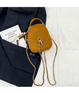 Détails d'un sac à dos en daim matelassé marron avec chaîne dorée et pendentif à perles