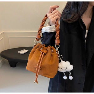 Détail du sac seau en daim marron avec anse en cuir tressé et pendentif nuage