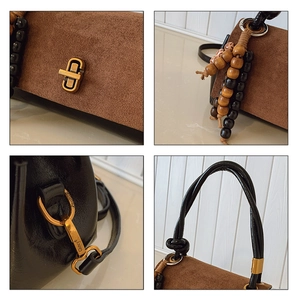 Detail of metal twist lock and woven wooden bead charm on black leather handbag