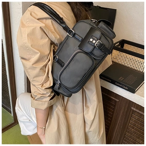 Detail of black leather shoulder bag with silver zippers and multi-pocket design on side