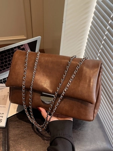 Braune Vintage Kunstledertasche mit Kettenriemen und weichem Falten-Design in Lifestyle-Umgebung