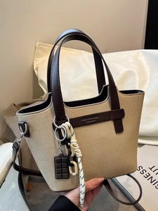 Fashionable beige canvas tote bag with brown leather trim and retro charm pendants