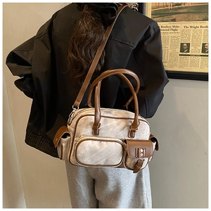 Close-up of beige vintage bowling bag with brown leather trim worn as a crossbody