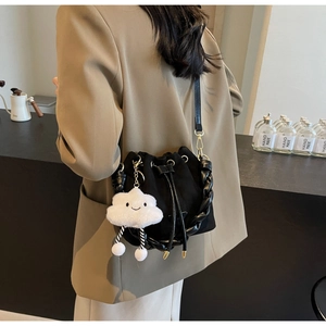 Détail du sac seau noir avec poignée tressée et accessoire de charme nuage en peluche