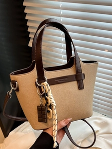 Beige canvas tote bag with brown leather trim and adjustable strap in a modern style