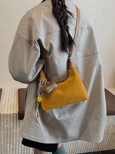 Ingwergelbe Halbmond-Achseltasche mit Deko-Anhängern an einem Model präsentiert