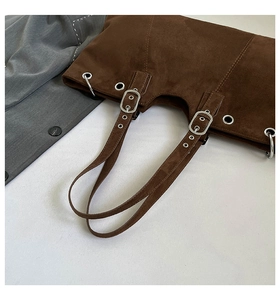 Detail of dark brown suede tote bag featuring silver eyelets and adjustable strap buckles