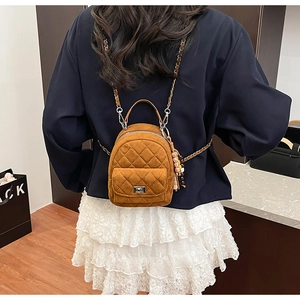 Détail du sac à dos matelassé en daim caramel avec chaîne et pendentif pompon