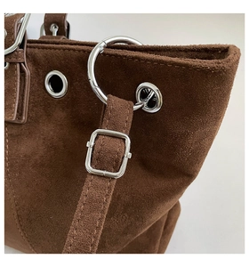 Detail of dark brown suede tote bag featuring silver metal rings and precise stitching