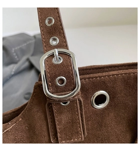 Detail of dark brown suede strap with silver metal buckle and reinforced eyelets