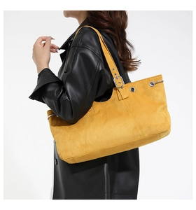 Detail of yellow suede tote bag featuring silver hardware and adjustable wide shoulder strap