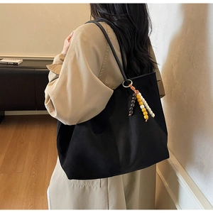 Detail of black large capacity tote bag with decorative colorful wooden bead tassel