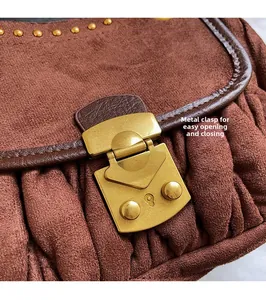 Macro view of brown suede handbag with vintage gold metal clasp and pleated leather detail