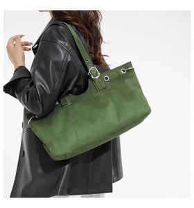 Detail of dark green suede tote bag with silver eyelets and adjustable strap on model