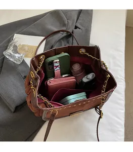 Top view of spacious brown tote interior holding phone, wallet, perfume, and daily essentials