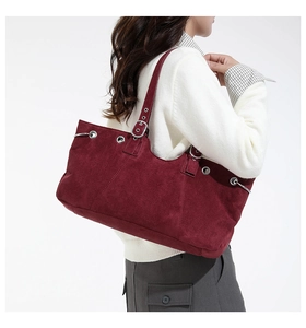 Detail view of burgundy faux suede tote bag with silver eyelets and buckle strap