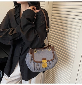 Detail of grey-blue pleated shoulder bag with brown leather trim and gold studs