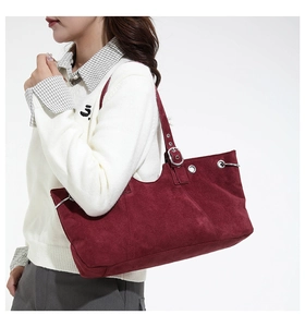 Detail of burgundy suede tote bag showing silver metal eyelets and textured material